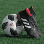 Football and football boots on green astroturf.