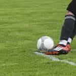 A footballer about to kick a football on a pitch.