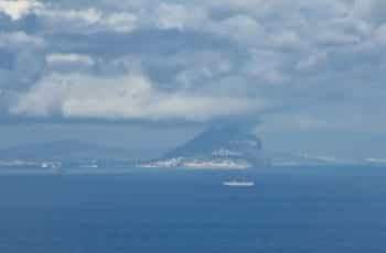 A cloudy ocean shore from the sea reveals the Rock of Gibraltar.